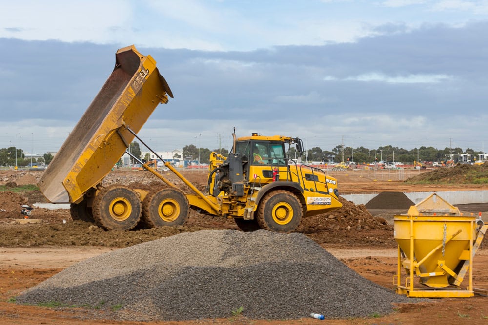 Large dump truck at a construction site with piles of limestone aggregate and other aggregate